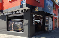 Fachada de Mr. Pedro Barbería VIP en una esquina: planta baja negra con las letras de la barbería, logo dorado circular sobre la entrada y gráfico promocional en el ventanal